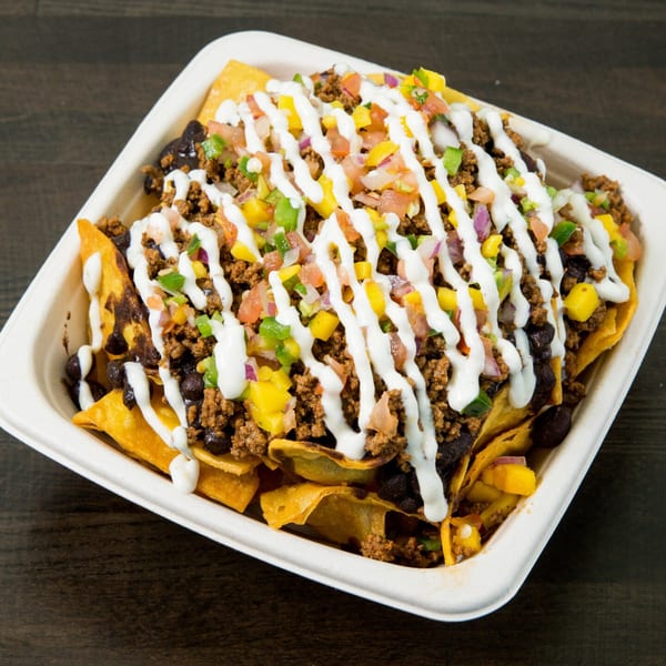 Nachos with ground beef, black beans, corn, pico de gallo, and a drizzle of white sauce.