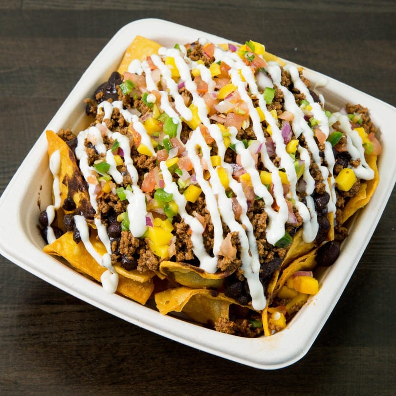 Nachos with ground beef, black beans, corn, pico de gallo, and a drizzle of white sauce.
